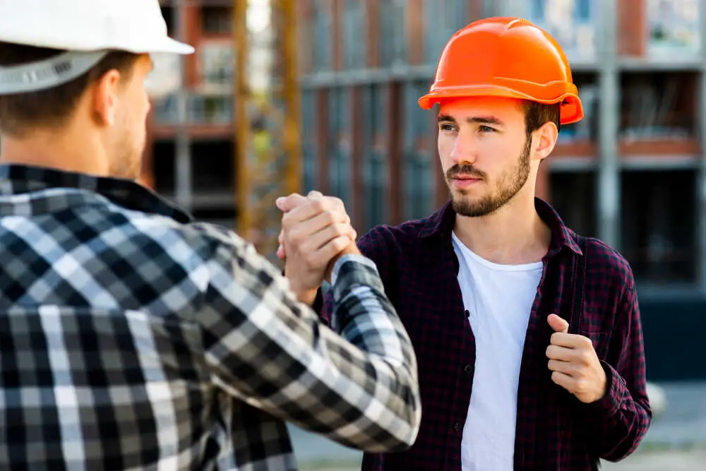 Inżynier podaje ręke pracownikowi firmy budowlanej